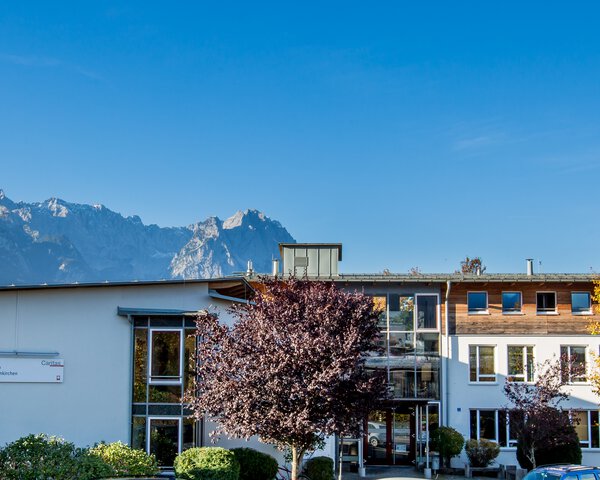 Ein Gebäude und dahinter die Berge von Garmisch | © Ferdinand Brunnenmayer
